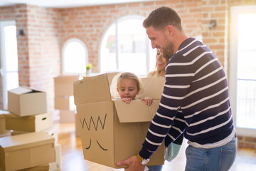 Beautiful famiily, kid playing with his parents riding fanny cardboard box at new home