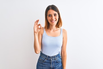 Beautiful redhead woman standing over isolated background smiling positive doing ok sign with hand and fingers. Successful expression.