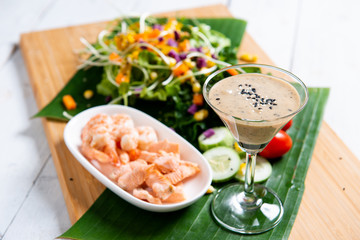 Fresh salad plate with shrimp, salmon, tomato and mixed greens  on wooden background .