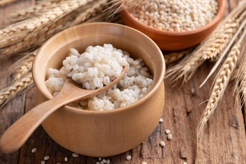 Cooked peeled barley grains in wooden bowl