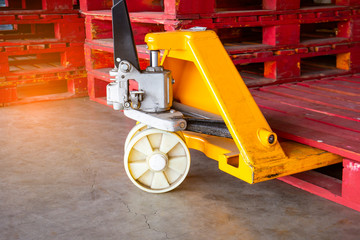 Yellow hand pallet truck with red wooden pallet