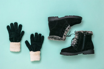 Knitted gloves and winter women's boots on a blue background. Flat lay.