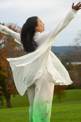 Woman dancing outdoors wearing a white cape in western Massachusetts.