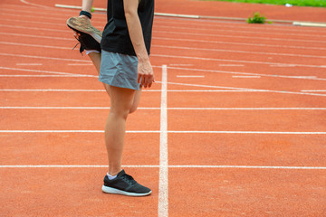 Cropped shot view of runner woman doing stretching and warming up her legs before running in the...