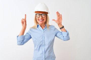 Middle age architect woman wearing glasses and helmet over isolated white background showing and pointing up with fingers number six while smiling confident and happy.