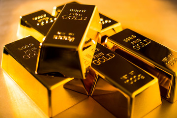 Shiny fine gold bullions on a gold background.