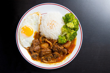 beef Curry Rice on black wooden background ( Onsen tamago, Potato, enoki mushroom, onion, broccoli, Japanese style)
