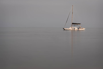 Anchored Caribbean sailboat at dusk on isolated simple background.
