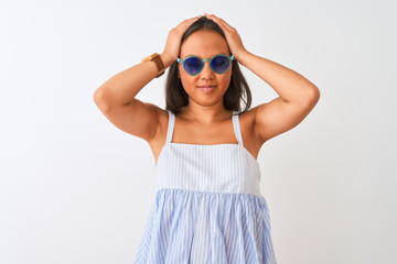 Young chinese woman wearing striped dress and sunglasses over isolated white background suffering from headache desperate and stressed because pain and migraine. Hands on head.