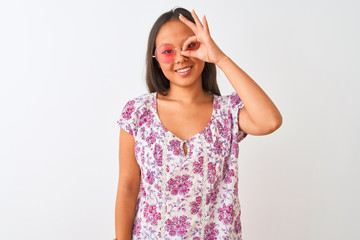 Obraz na płótnie Canvas Young chinese woman wearing floral t-shirt and pink glasses over isolated white background doing ok gesture with hand smiling, eye looking through fingers with happy face.