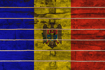 National flag  of Moldova on a wooden wall background. The concept of national pride and a symbol of the country. Flags painted on a wooden fence with a rope