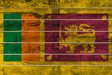 National flag  of Sri Lanka on a wooden wall background. The concept of national pride and a symbol of the country. Flags painted on a wooden fence with a rope