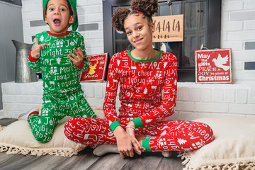 African american mixed with caucasian ethnicity siblings wearing holiday pajamas spending Christmas together.