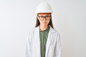 Young chinese engineer woman wearing coat helmet glasses over isolated white background skeptic and nervous, frowning upset because of problem. Negative person.
