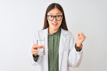 Young chinese dooctor woman wearing glasses drinking water over isolated white background screaming proud and celebrating victory and success very excited, cheering emotion