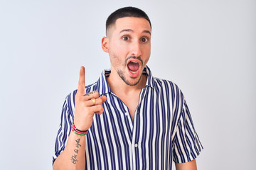 Young handsome man wearing nautical striped shirt standing over isolated background pointing finger up with successful idea. Exited and happy. Number one.