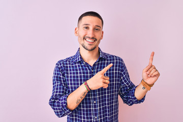Naklejka premium Young handsome man standing over isolated background smiling and looking at the camera pointing with two hands and fingers to the side.