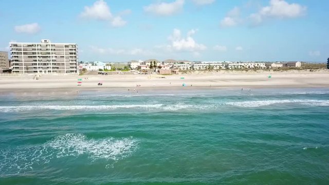 Aerial flying in from a tropical ocean over the seashore
