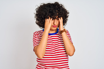Young arab woman with curly hair wearing striped t-shirt over isolated white background with hand on head for pain in head because stress. Suffering migraine.