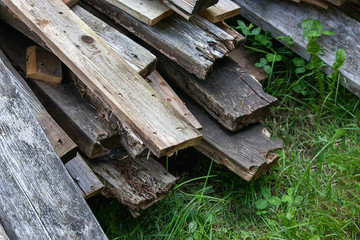 piles of mismatched old broken deck boards laying in grass