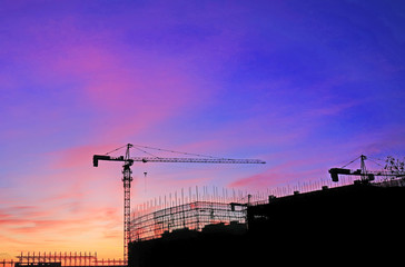 Cranes at construction sites, silhouetted at sunrise