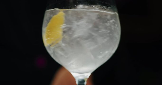 Close up of a professional bartender is mixing gin tonic with professional crystal ice cubes to customers at the bar or disco club. Close up of a professional bartender is mixing gin tonic with profes