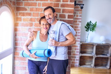 Middle age beautiful sporty couple doing yoga at gym