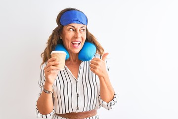 Tourist woman wearing neckpillow sleep mask drinking coffee over isolated white background pointing and showing with thumb up to the side with happy face smiling