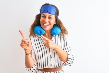 Middle age tourist woman wearing neckpillow and sleep mask over isolated white background smiling and looking at the camera pointing with two hands and fingers to the side.