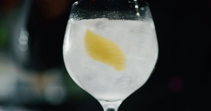 Close up of a professional bartender is mixing gin tonic with professional crystal ice cubes to customers at the bar or disco club.