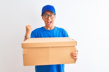 Senior deliverywoman wearing cap and glasses holding box over isolated white background screaming proud and celebrating victory and success very excited, cheering emotion