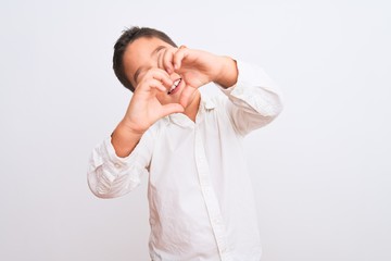 Beautiful kid boy wearing elegant shirt standing over isolated white background smiling in love showing heart symbol and shape with hands. Romantic concept.