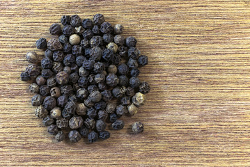 Spices. Whole grains of black pepper on the surface of a natural wooden beech board. Place for text, Copy-space on the right.
