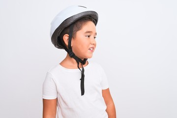 Beautiful kid boy wearing bike security helmet standing over isolated white background looking away to side with smile on face, natural expression. Laughing confident.
