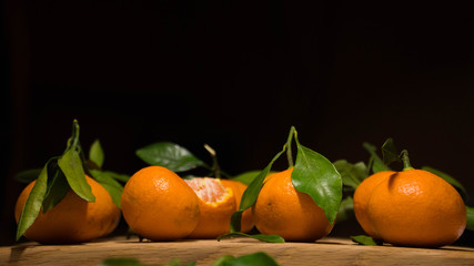 Tangerines with green leaves on the black background.  Preparation for the new year. New year mood. Christmas mood. new year's fruit. Christmas tradition.