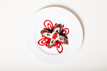 Chocolate roll with cream cheese and cherry decorated on a plate