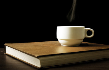 A white coffee cup warming up on the book