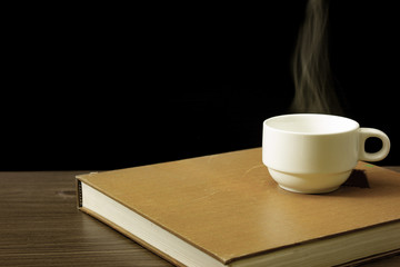 A white coffee cup warming up on the book