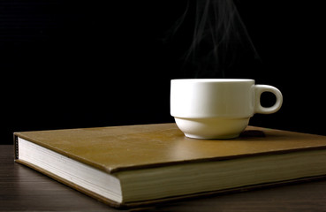 A white coffee cup warming up on the book