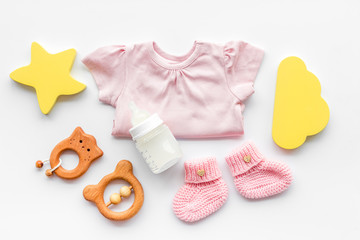 Newborn girl set - clothes as bodysuit, booties, toys - on white table top-down