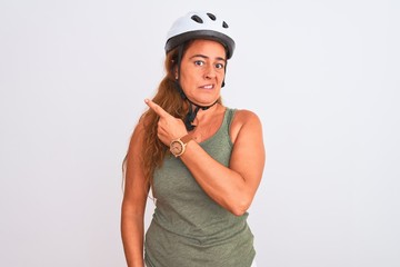 Middle age mature cyclist woman wearing safety helmet over isolated background Pointing aside worried and nervous with forefinger, concerned and surprised expression