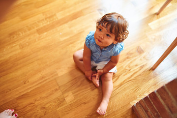 Naklejka premium Beautiful toddler child girl wearing blue denim shirt sitting on the floor