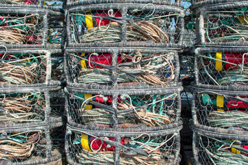 Commercial crab fishing cages with red and yellow buoys stacked on dock