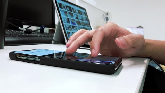 Man using mobile phone close-up hands at his office on the desk.Search social network and news modern technology concept.