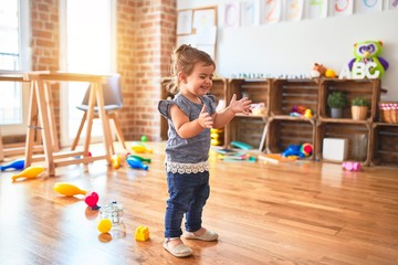 Beautiful toddler standing on the floor applauding and smiling at kindergarten