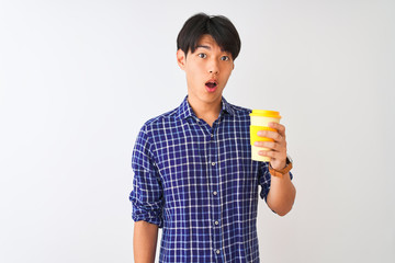 Young chinese man drinking take away coffee standing over isolated white background scared in shock with a surprise face, afraid and excited with fear expression