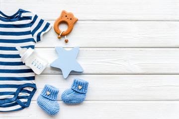 Newborn baby boy set - blue clothes as bodysuit, booties, toys - on white wooden table top-down frame copy space © 9dreamstudio