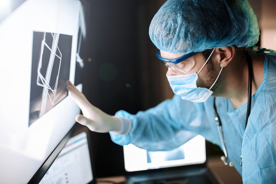 male surgeon orthopedic traumatologist touches a touch screen with a x-ray of the bone.