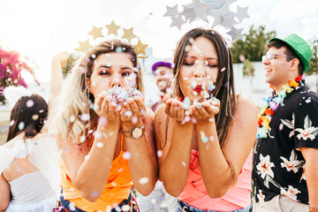 Brazilian Carnival. Young women in costume enjoying the carnival party blowing confetti