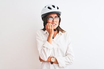Beautiful businesswoman wearing glasses and bike helmet over isolated white background looking stressed and nervous with hands on mouth biting nails. Anxiety problem.